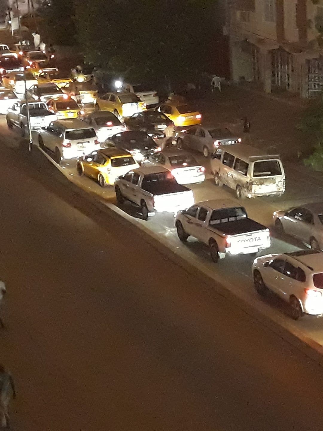 Circulation du soir à N'Djamena, voitures et taxis en file sous les lampadaires